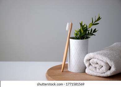 Eco Bamboo Tooth Brush Near White Holder And White Rolled Towel On Wooden Round Board. Dental Treatment Or Oral Cavity Care Concept. Copy Space.