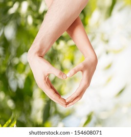 eco, bio, nature, love, harmony concept - woman and man hands showing heart shape