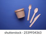 Eco cardboard round food box with wooden spoon, fork, knife on blue background