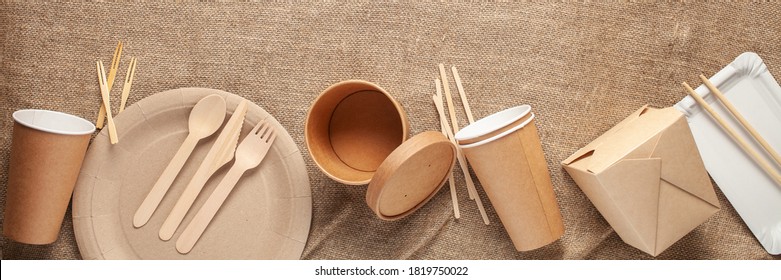 Eco craft paper tableware. Paper cups, dishes, bag, fast food containers and wooden cutlery on wooden background. Recycling concept. Banner. Top view.  - Shutterstock ID 1819750022