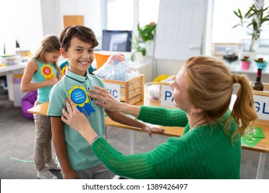 Eco friendly award. Beaming handsome schoolboy feeling amazing receiving eco friendly award at school - Powered by Shutterstock