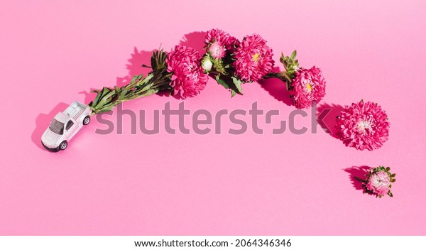 Eco friendly car on bright pink background. Car\
driving leaving behind fresh environment and vibrant pink flower. \
Minimal nature love\
concept.
