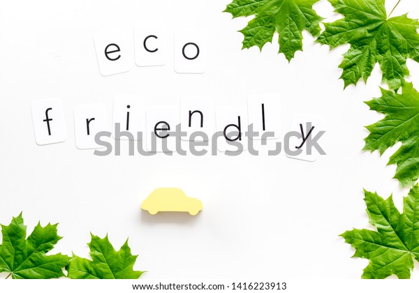 eco friendly concept with maple\
leaves, car and lamp on white background top\
view