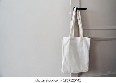 Eco friendly concept with white canvas tote bag hanging on door knob with two toned colored, Eco blank shopping sack with free copy space, Reduce plastic bags to reduce global warming. Canvas tote bag - Powered by Shutterstock