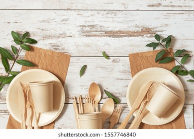 Eco friendly disposable dishes made of bamboo wood and paper on white wooden background. Zero waste, eco friendly, plastic free background.