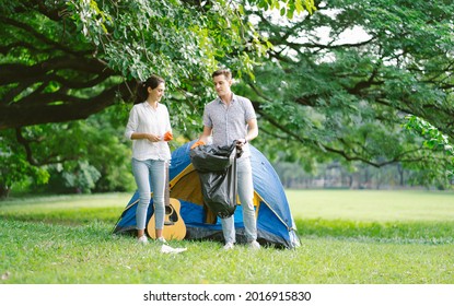 Eco Friendly Happy Couple Wearing Orange Gloves Cleans Plastic And Garbage Picking Up Litter In The Forest Or Park While Camping. Problems Of Environmental Pollution And Nature.