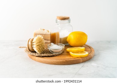 Eco friendly natural cleaners, jar with baking soda, dish brush, lemon, soap on white marble table background. Organic ingredients for homemade cleaning. Zero waste concept.