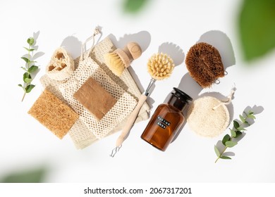 Eco friendly natural cleaning tools and products, bamboo and coconut dish brushes, luffa loofah sponges, baking soda and solid soap on white background. Zero waste concept