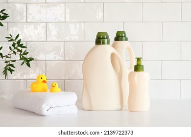 Eco friendly organic natural baby laundry detergent and soap gel bottle with branch of green leaves, towel and yellow duck on table in bathroom. Baby hygiene products packaging design, branding.