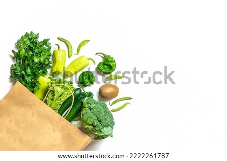 Eco friendly paper shop bag with raw organic green vegetables isolated on white background Flat lay, top view Zero waste, plastic free concept Healthy clean eating diet and detox, agriculture concept.