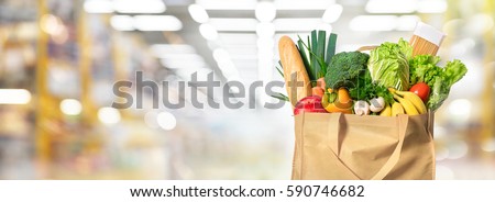 Eco friendly reusable shopping bag filled with vegetables on a blur background