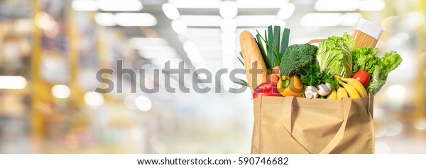 Eco friendly reusable shopping bag filled with
vegetables on a blur
background