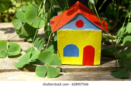 Eco House Of Luck. Colorful Paper House In The Middle Of Four Leaf Clover Vegetation.