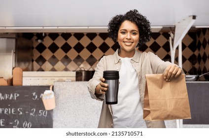 Eco Living, Eating And Sustainability People Concept - Happy Smiling Woman With Thermo Cup And Takeaway Paper Bag Over Food Truck Background