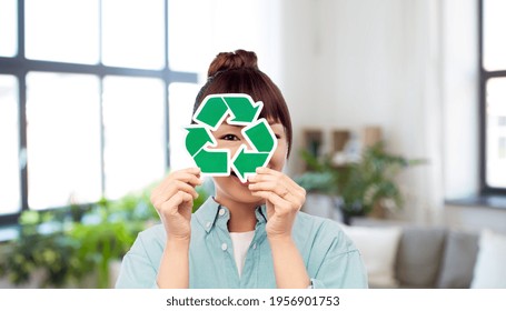 eco living, environment and sustainability concept - portrait of happy smiling young asian woman in turquoise shirt holding green recycling sign over home background - Powered by Shutterstock