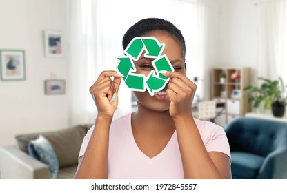 eco living, environment and sustainability concept - portrait of happy smiling young african american woman looking through green recycling sign over home room background - Shutterstock ID 1972845557