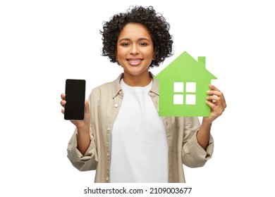 Eco Living, Environment And Sustainability Concept - Happy Smiling Woman Holding Green House And Smartphone Over White Background