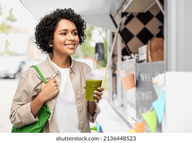 Eco Living, Zero Waste And Sustainability Concept - Portrait Of Happy Smiling Young Woman With Green Reusable Shopping Bag Drinking Takeaway Smoothie Or Shake Over Food Truck Background