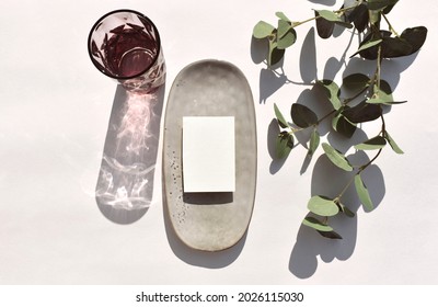 Eco Minimal Still Life Scene.  Empty Blank On Ceramic Plate, Cocktail Glass And Eucalyptus Leaves On Neutral Background. Mockup Invitation Card For Wedding, Event Data Or Menu. Sunlight, Long Shadow