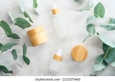 Eco Natural Cosmetics Products Set In Transparent And Bamboo Containers On Marble Stone Background With Eucalyptus Branches. Flat Lay, Top View. Beauty Products Packaging Design, Branding.