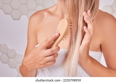 eco natural hair care - blonde woman combs her hair in bathroom. Beauty routine concept - Shutterstock ID 2235798959