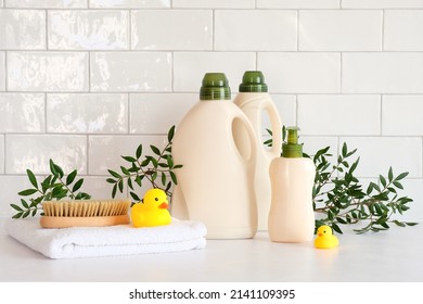 Eco organic laundry detergent bottles packaging design. Clean detergent bottles, towels, brush, duck toys, green leaves on table. - Shutterstock ID 2141109395