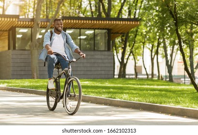 Eco Ride. Happy african american man riding bicycle in city, going to work, enjoying sunny weather, free space