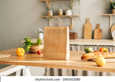 Eco Shopping Paper Bag With Fresh Vegetables And Baguette On The Table In Modern Kitchen. Food Delivery Or Market Shopping Concept.