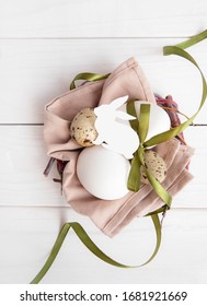 Eco style easter composition on white wooden background. Eggs with green ribbon and paper rabbit. Flatlay 