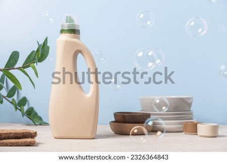 Eco-friendly dishwashing. Bottle with detergent and bamboo eco sponges on blue background with soap bubbles