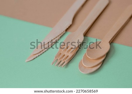 Eco-friendly disposable kitchen utensils on a beige-green background. Wooden forks, spoons and knives. Ecology, the concept of zero waste.