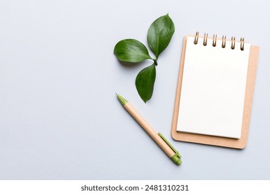 eco-friendly Empty notebook with pen and green leaf on Colored background for note.