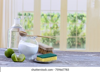 Eco-friendly natural cleaners baking soda, lemon and cloth on wooden table windows background,