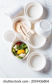 Eco-friendly recyclable tableware, zero waste concept. Paper bowls and cups on white marble background, top view.