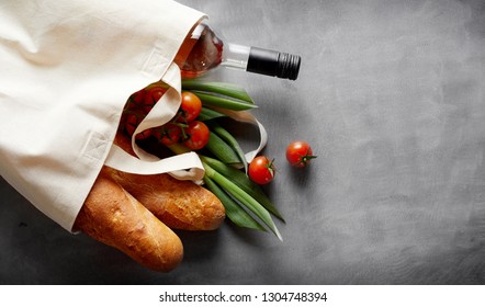 Eco-friendly reusable textile bag with groceries and wine spilling out onto a slate background with copy space - Powered by Shutterstock