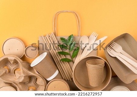 Eco-friendly tableware bundle over orange background - sustainable paper food packaging. Street food paper packaging, recyclable paperware, zero waste packaging concept
