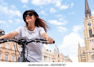 Eco-friendly tourism, young urban woman using green transportation while traveling European city. Woman biking around town and smiling. - Powered by Shutterstock