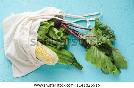 Ecological bag with vegetables on blue background