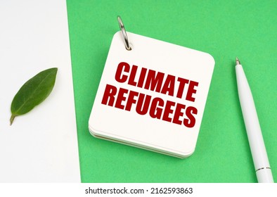 Ecological Concept. On A White-green Surface, A Piece Of Paper, A Pen And A Notepad With The Text - Climate Refugees