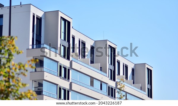 Ecological housing architecture. A modern\
residential building in the vicinity of trees. Ecology and green\
living in city, urban environment concept. Modern apartment\
building and green\
trees.