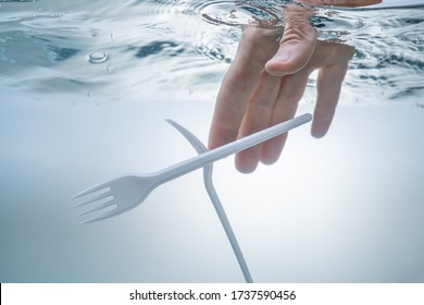 Ecological problem of water pollution, the environment. Hand pulling out plastic forks.