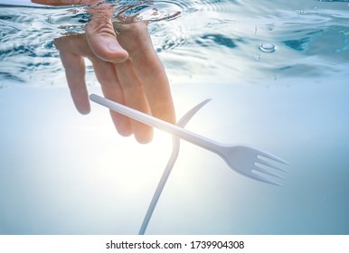Ecological problem of water pollution, the environment. Hand pulling out plastic forks.