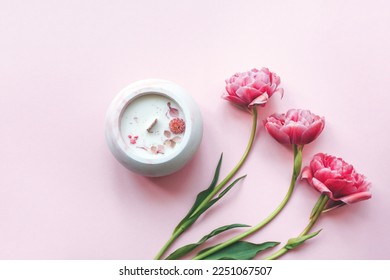 Ecological and vegan handmade candle with dry flowers  in a glass made of concrete on a pink background with pink tulips. Soy or coconut candle with a wooden wick. - Shutterstock ID 2251067507