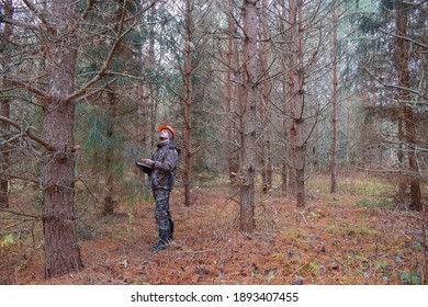 An ecologist with a computer in his hands observes the development of the forest. The concept of afforestation in forestry. Selective focus on a worker in a helmet. - Shutterstock ID 1893407455
