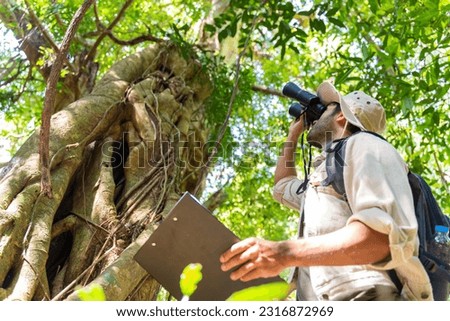 Ecologist,national park,forester,environmental conservation concept.man park ranger in uniform looks through binoculars and monitoring the forest area in summer or autum. 