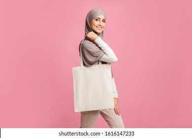 Ecology Concept. Muslim Girl In Hijab With Blank Eco Tote Bag Over Pink Studio Background, Free Space