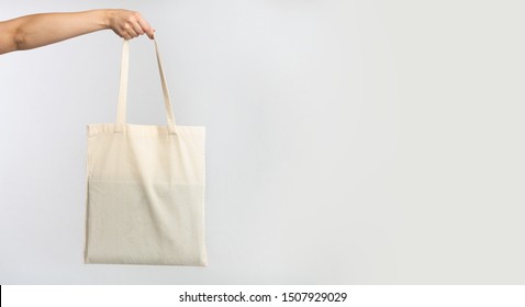 Ecology. Female Hand Holding White Blank Canvas Tote Bag, Studio Background. Panorama, Copy Space