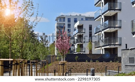 Ecology and green living in city, urban environment concept. Modern apartment building and green trees. Ecological housing architecture. A modern residential building in the vicinity of trees.
