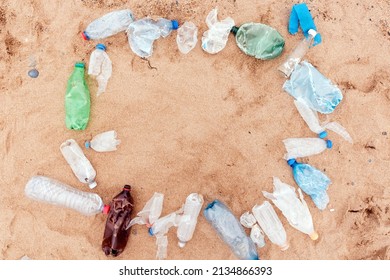 Ecology Template. Frame From Plastic Dirty Bottles With Copy Space On A Sandy Beach. Top View. The Concept Of Environmental Protection And Earth Day.