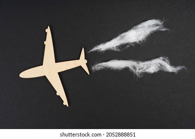 Ecology And Transportation Concept. The Plane Flies And Leaves Behind Traces Of Emissions. Isolated On Black Background.